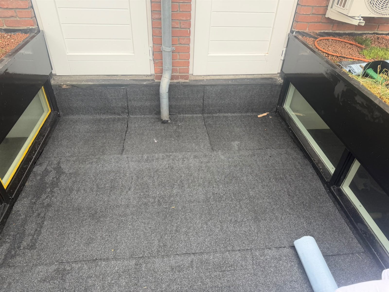 Overzicht van bitumen dakbanen en afvoeren op een laag plat dak