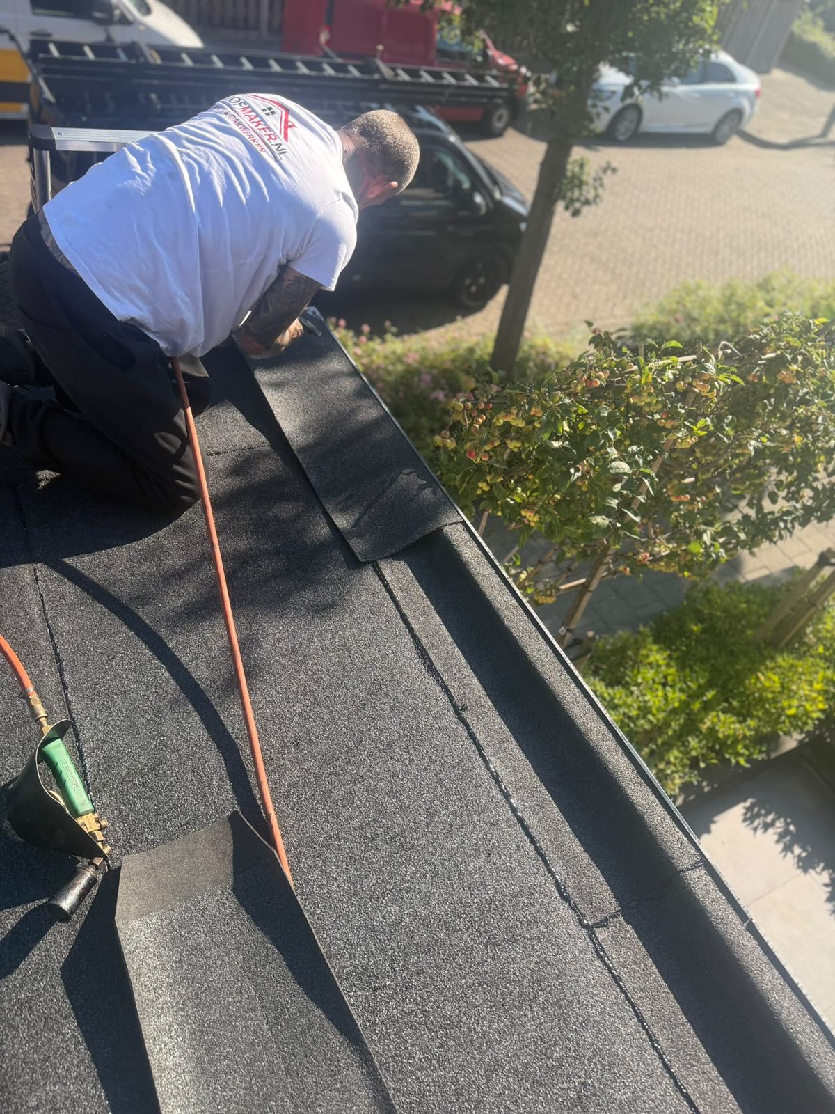 Roofmaker dakdekker werkt op de nieuwe bitumen dakbedekking van een aanbouw
