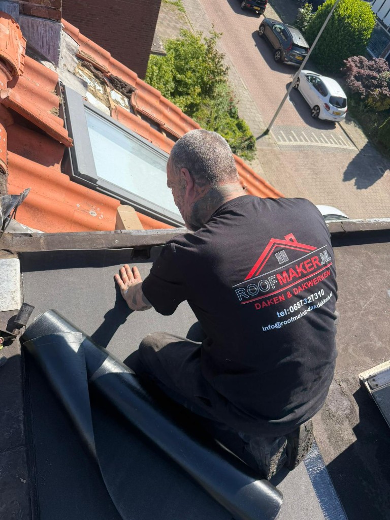 Dakdekker legt bitumen rol aan op plat dak